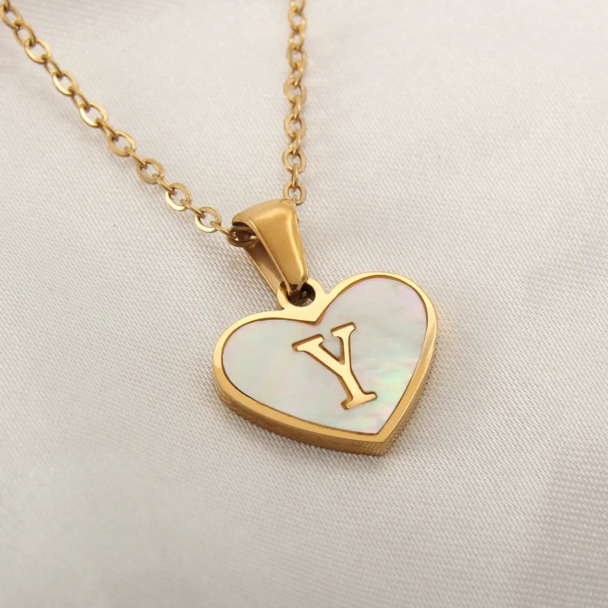 Gold-plated heart necklace with white shell pendant showing initial engraving on stainless steel chain