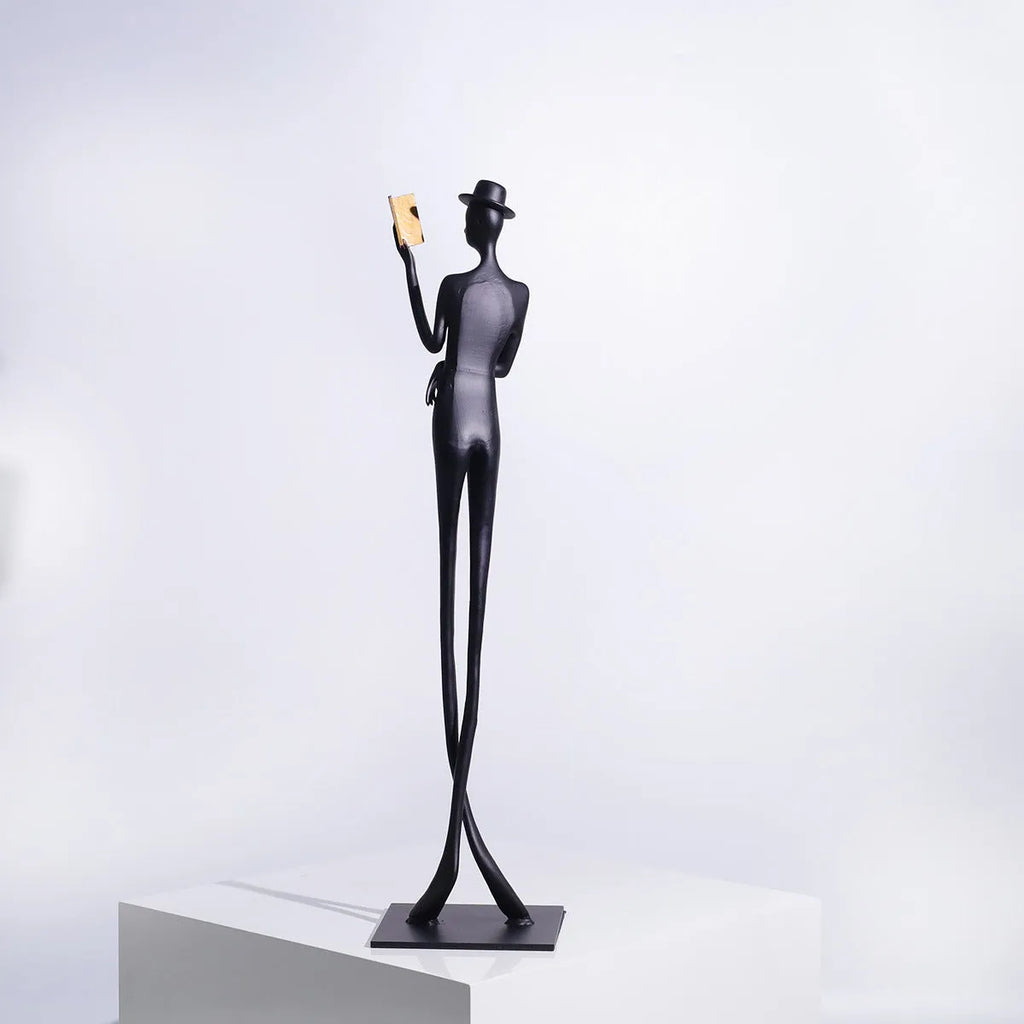 Black cast aluminium sculpture of a woman reading, modern minimalist desk decor.