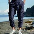 Man wearing khaki linen casual trousers with ankle-tied cuffs and multiple pockets.