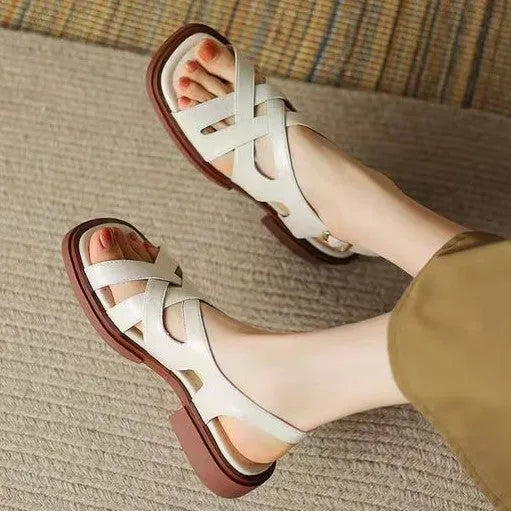 Women's black patent leather square toe sandals with cross strap on a white background.