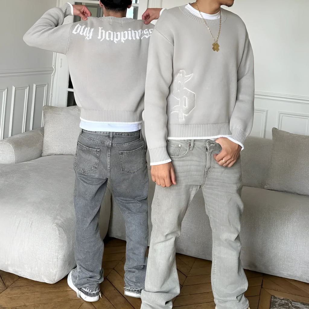 Grey loose-fitting jacquard knit coat on a hanger, showing long sleeves and textured knit pattern.