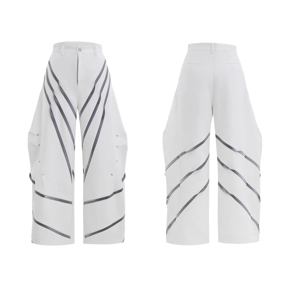 Men's black trousers with white pleated detail and silver metal striped rivets, showing the three-dimensional cut.
