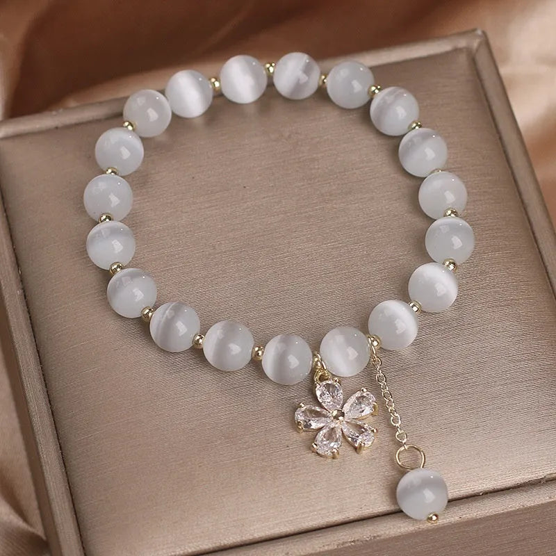 Women's single loop bracelet with white cat's eye stones and decorative tassel featuring morganite safety buckle