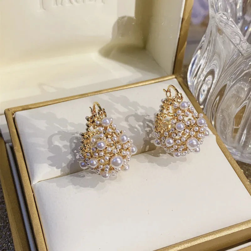 Gold tone copper flower basket earrings with small rice-shaped beads and a central pearl inlay.