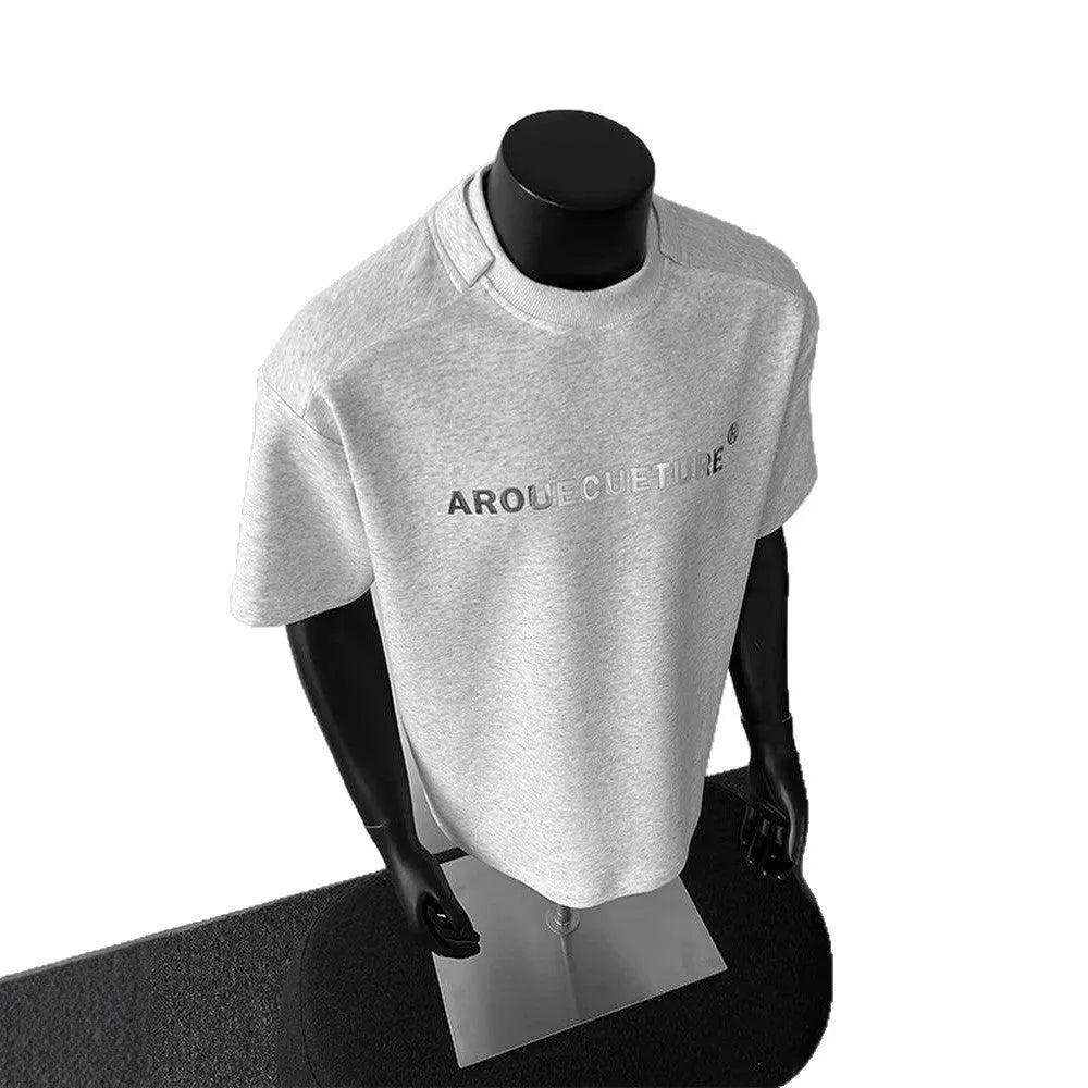 Man wearing a loose grey short sleeve cotton shirt with a letter print design.
