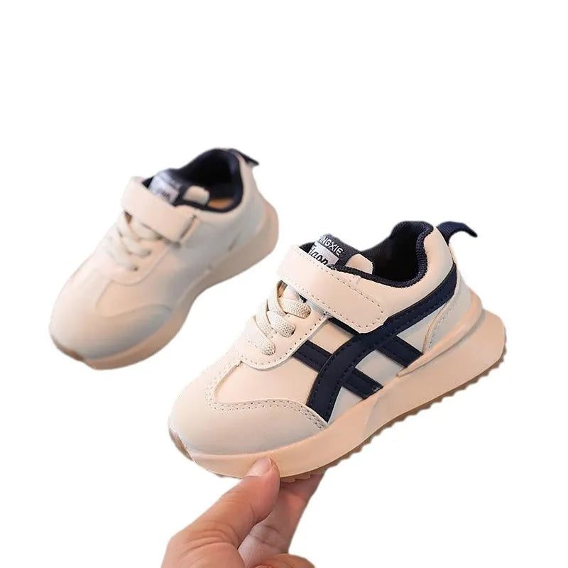 Children's white sneakers with Velcro fastening and rubber sole shown from side view