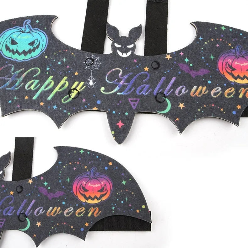 Black cat wearing an orange felt batwing Halloween costume with bell.