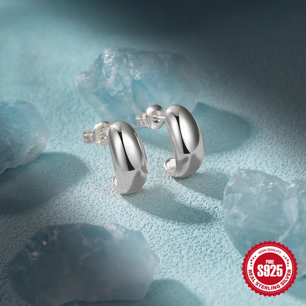 Close-up of a glossy C-shaped sterling silver stud earring in a gold electroplated finish.