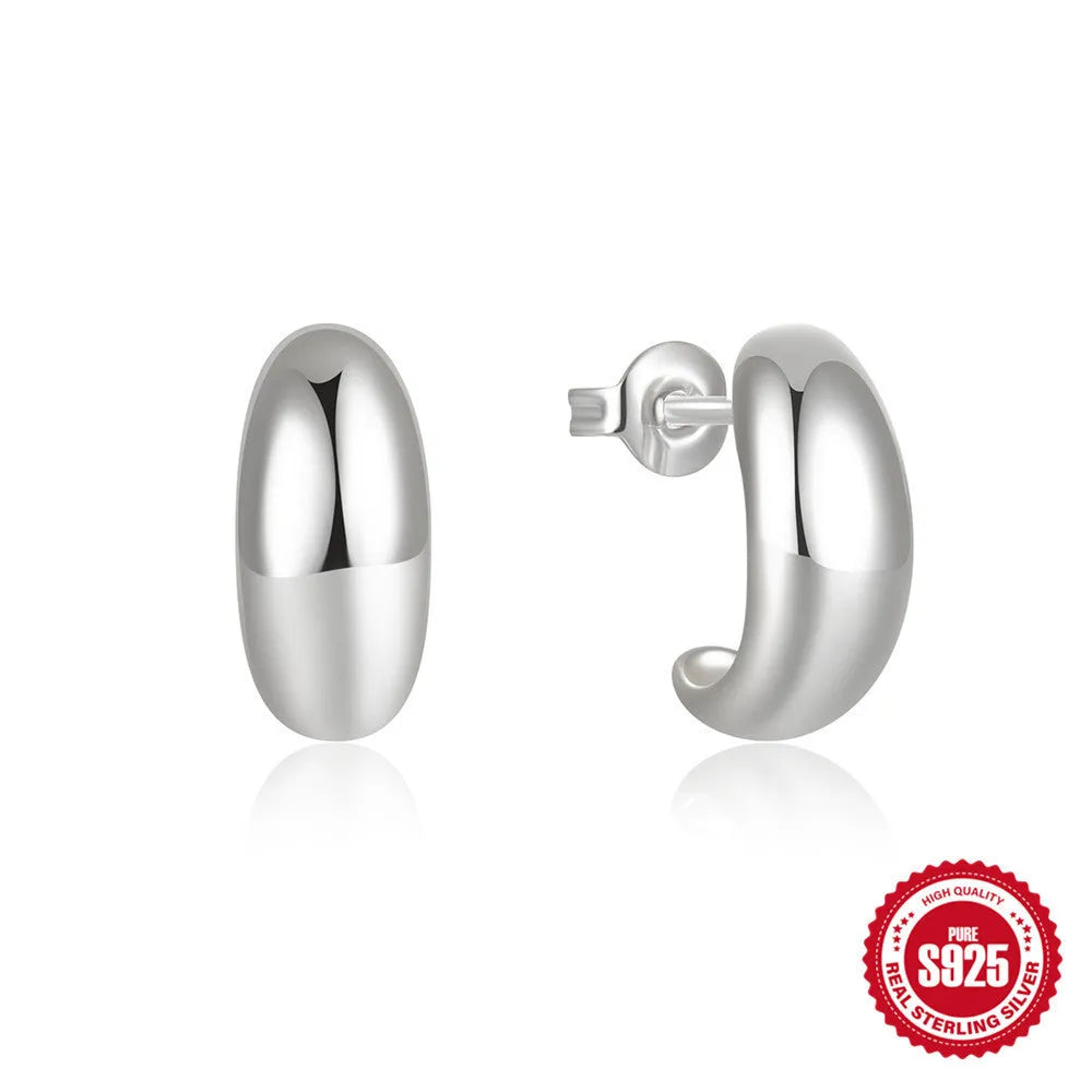 Close-up of a glossy C-shaped sterling silver stud earring in a gold electroplated finish.