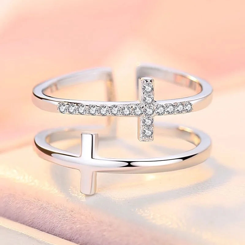 Adjustable open copper ring with geometric double cross design and inlaid zircon stones in gold colour finish.