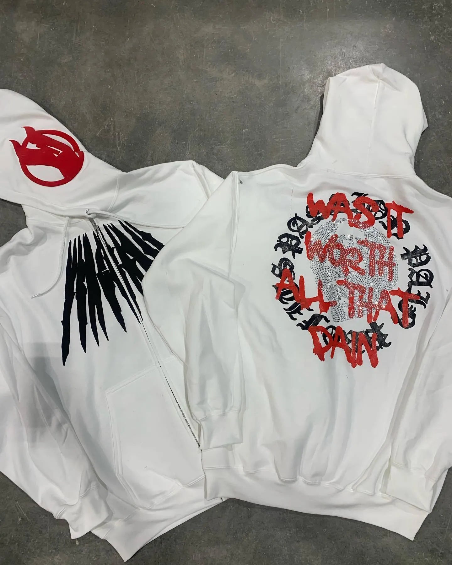 Black loose hooded sweatshirt with white printed skull design and rhinestone details on the front.