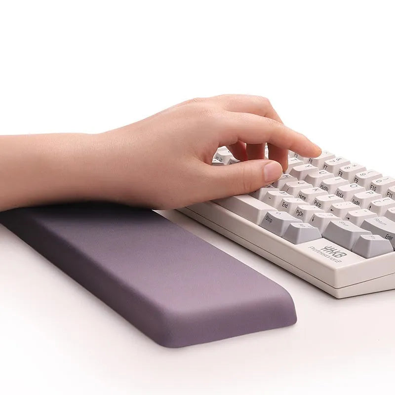 Square black silica gel mouse pad with raised keyboard support area and integrated wrist rest on a wooden desk.