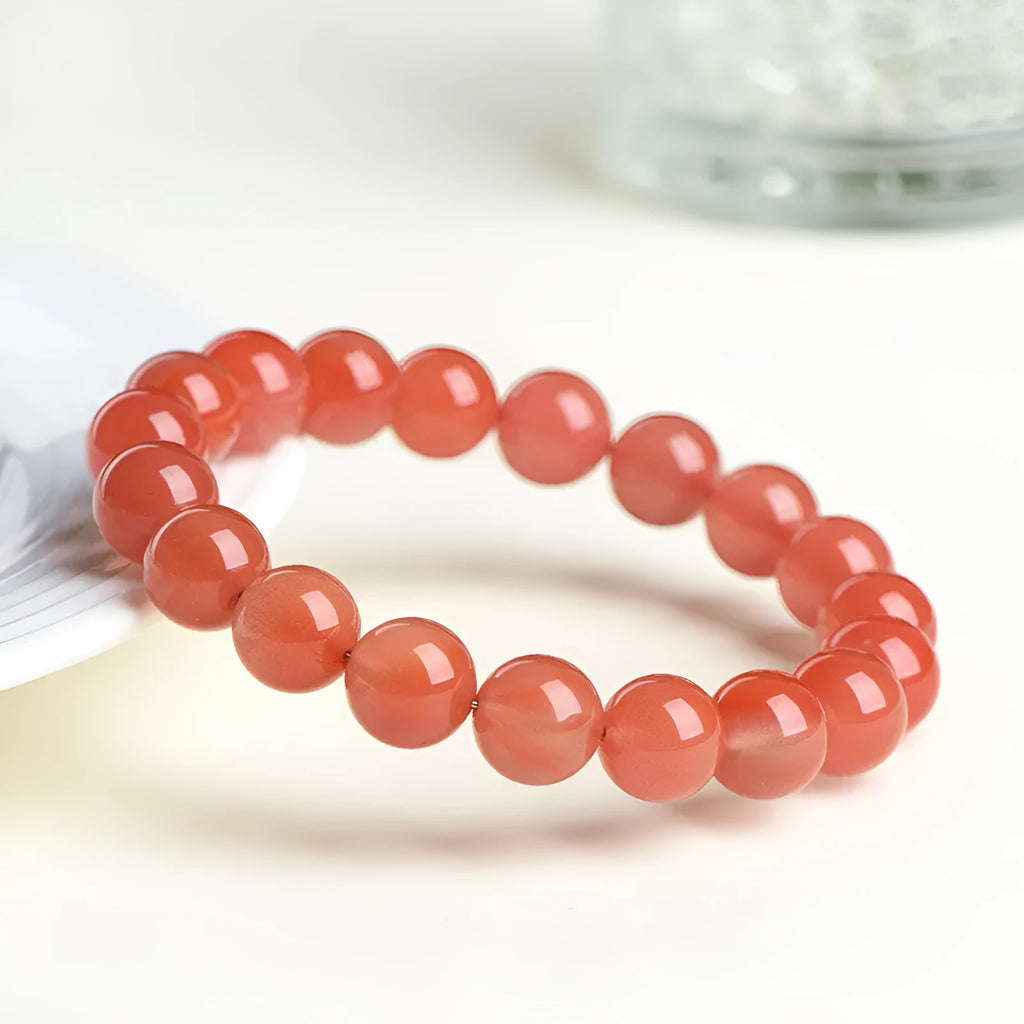 Natural South cherry red agate bracelet showing polished stone beads in scattered arrangement
