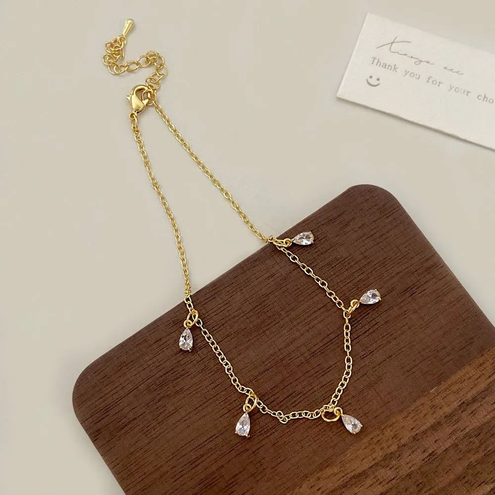 Women's zircon jewellery set showing geometric necklace, earrings, and anklet with meteor shower detail.