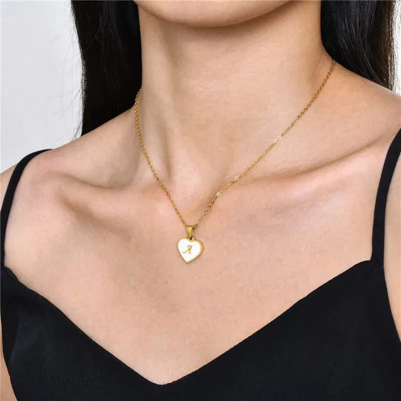 Gold-plated heart necklace with white shell pendant showing initial engraving on stainless steel chain