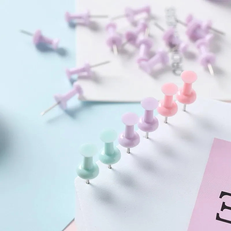 Plastic push pins in cherry blossom pink, mint green, and lavender, showing large and small sizes on a corkboard